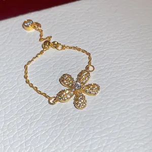 Dettaglio ravvicinato di un anello a catena d'oro con un fiore in zircone a 5 petali.