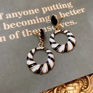 Detail view of black and white striped geometric round earrings with a polished gold finish