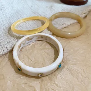 Detail shot of three-piece resin bangle set with colorful crystals and marble texture