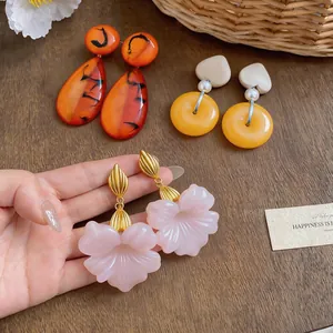 Close-up of elegant French vintage resin earrings with floral and teardrop motifs