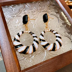 Detailed macro view of geometric earrings with black and white enamel spiral stripes