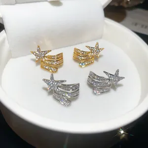 Close-up of gold and silver zircon star ear clips without piercing in a jewelry box.