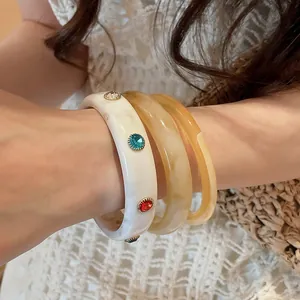 Detailed macro view of a 3-piece resin bangle set featuring colorful inset gemstones