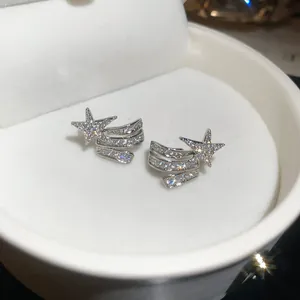 Close-up of elegant silver star-shaped zircon earrings displayed in a white jewelry box.