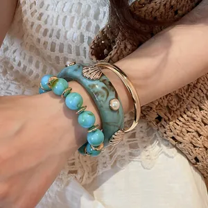 Close-up of 3-piece resin bracelet set with blue marble finish and golden shell accents