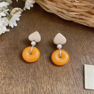 Detailed view of French vintage earrings featuring heart wood and orange resin rings