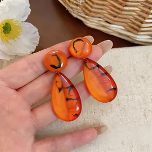 Detailed view of French vintage resin drop earrings with marbled orange pattern