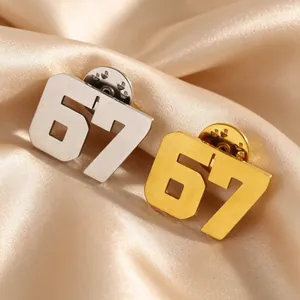 Dettaglio ravvicinato di spille numero 67 in acciaio inossidabile oro e argento.