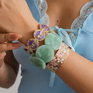 Close-up of vintage butterfly metal bracelets and green resin bangle on woman's wrist