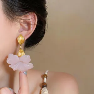 Close-up of pink resin flower earrings with gold leaf stud on an Asian model's ear.
