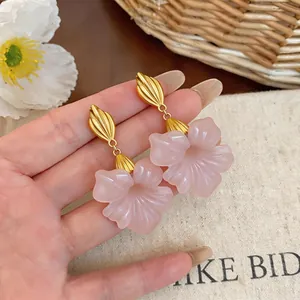 Close-up view of pink resin flower earrings with vintage gold-toned metal leaf studs