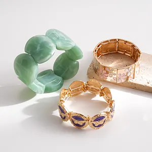 Close-up of vintage butterfly and floral enamel bracelets with green resin bangle.
