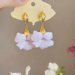 Detail view of French vintage earrings with pink resin petals and gold finish.