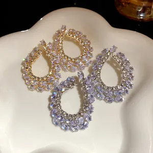 Gros plan de boucles d'oreilles géométriques en goutte avec zircons étincelants