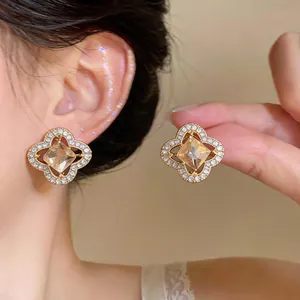 Detailed macro view of elegant gold flower earrings with amber stone and pavé crystal accents