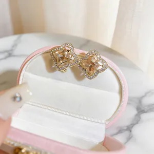 Close-up of champagne stone flower stud earrings with diamond-set hollow frame.