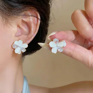 Close-up of elegant flower stud earrings with white petals and sparkling zircons