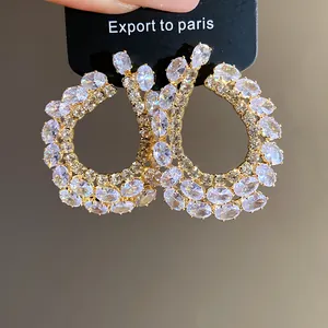 Gros plan d'élégantes boucles d'oreilles goutte en or ornées de zircons clairs.