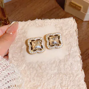 Close-up of gold-plated flower stud earrings with champagne crystals and pavé diamonds.