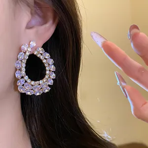 Gros plan sur d'élégantes boucles d'oreilles créoles avec zircons et aiguilles en argent.