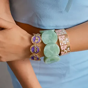 Close-up of three stacked stylish bracelets featuring butterfly, marble, and flower motifs.