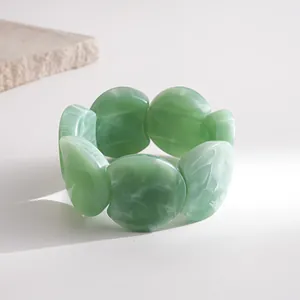 Close-up of a green marbled chunky acrylic elastic bracelet with a retro design