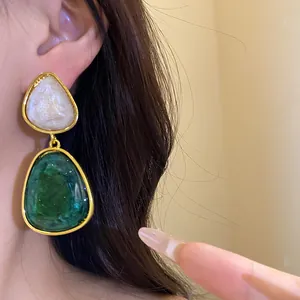 Close-up of vintage resin triangle pendant earrings in emerald green and pearl white