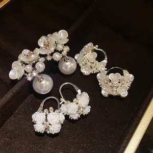 Close-up of elegant French vintage earrings with white flowers, pearls, and rhinestones.