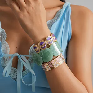 Detail view of stylish stacked butterfly enamel and floral bracelets on a model's wrist