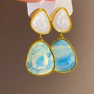Close-up of vintage resin dangle earrings featuring unique blue and white swirl pattern