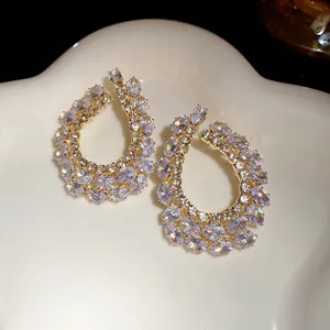 Vue détaillée de boucles d'oreilles goutte géométriques serties de zircons étincelants.