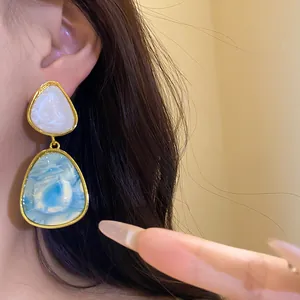 Close-up detail of vintage resin drop earrings with blue marbled texture on ear