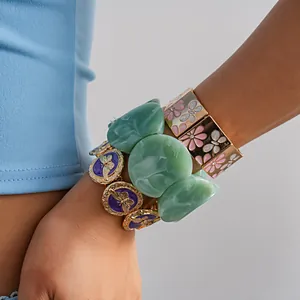 Close-up of stacked vintage bracelets featuring butterfly drip oil and floral designs