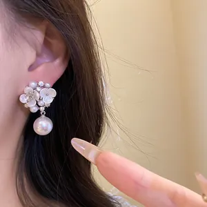 Detailed macro view of an elegant French style pearl flower drop earring on ear.