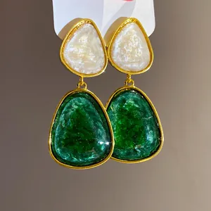 Macro detail of vintage green resin triangle drop earrings with elegant golden border