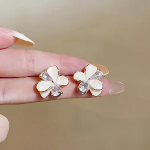 Close-up of elegant floral stud earrings with white petals and sparkling zircons