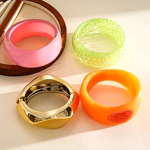 Close-up detail of stylish colorful resin and geometric golden metal bangles