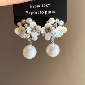 Close-up of elegant French retro pearl flower drop earrings with rhinestones.