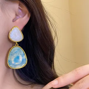 Detail view of vintage-style resin drop earrings with blue marble pattern