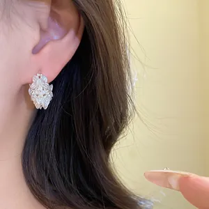 Detailed view of elegant pearl flower drop earring with rhinestones on model's ear