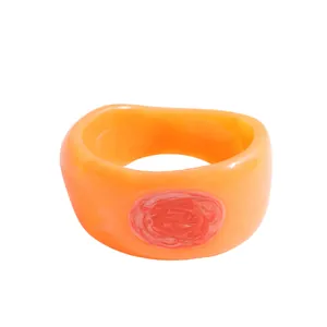 Statement orange resin bangle featuring a unique reddish-pink marble swirl center detail