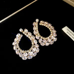 Détail en gros plan de boucles d'oreilles géométriques avec des zircons étincelants.