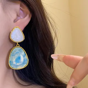 Close-up of vintage resin pendant earrings with blue marble effect