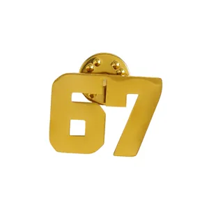 Dettaglio macro di una spilla in oro inox a forma di numero 67 con chiusura a farfalla