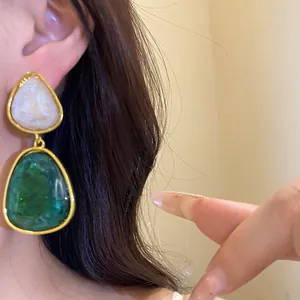 Close-up of vintage emerald green and white resin teardrop earrings worn on ear