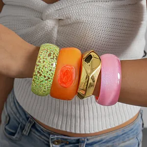 Close-up of vibrant resin and metallic geometric bangles with glitter and floral textures