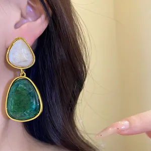 Macro view of minimalist vintage green and white resin drop earrings worn on a model's ear