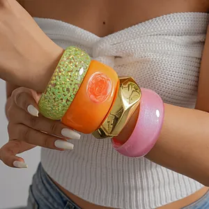 Detailed shot of chunky colorful resin and gold-tone geometric metal bracelets