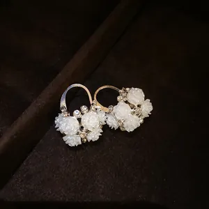 Close-up of French retro earrings with white resin flowers and rhinestones on velvet.