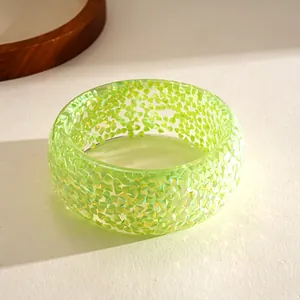 Close-up of a neon green resin geometric bangle with iridescent triangle patterns.